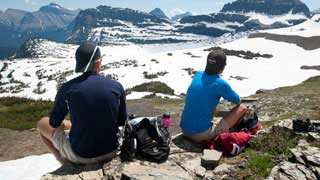 Two men sitting on a rock overlooking a cliff